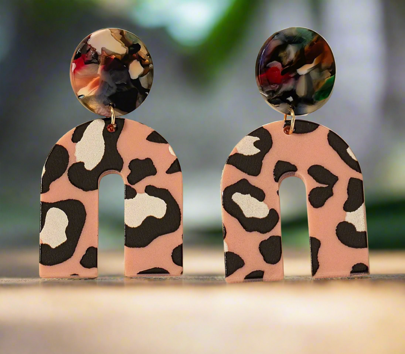 The Catalina earrings by Desiree W.A.R Store showcase a leopard print on the lower halves with vibrant, multicolored marble effect round tops, beautifully set against a light surface.