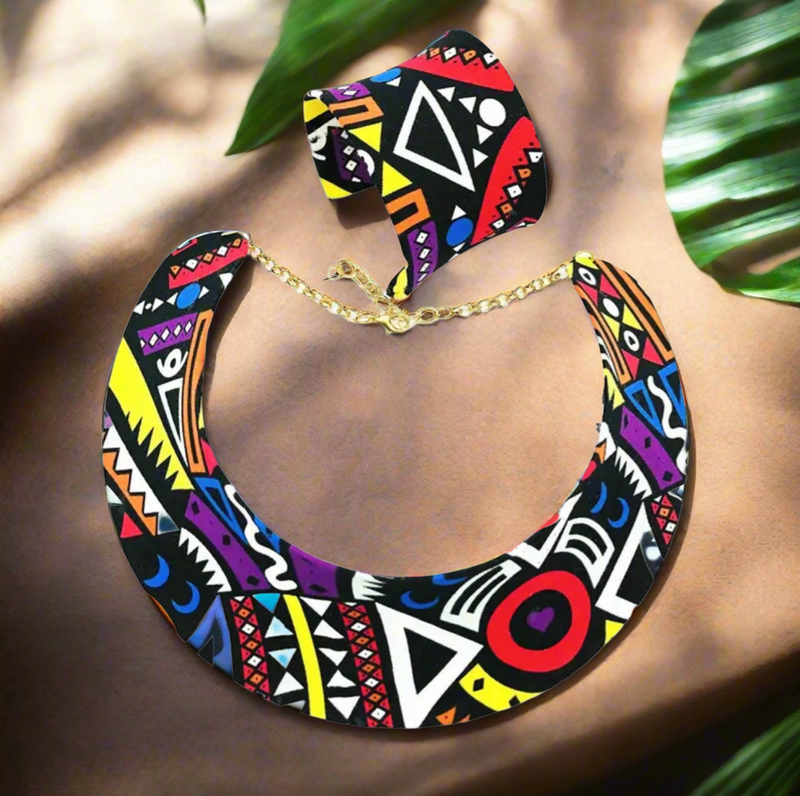 Colorful African tribal pattern bib necklace with matching round stud earrings, featuring geometric shapes in red, yellow, black, white, purple, and orange with gold-tone adjustable chain.