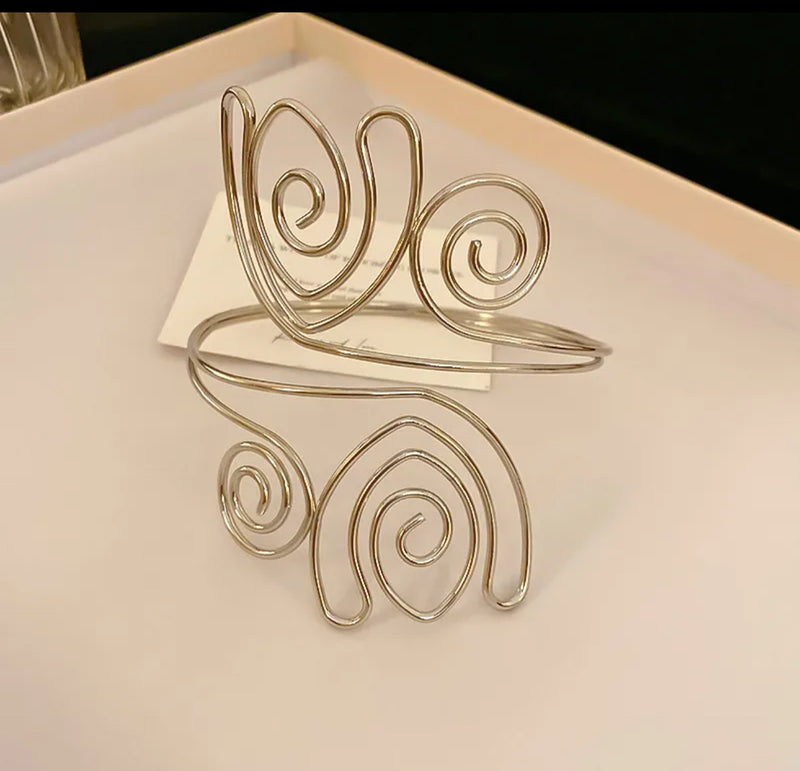 Silver-tone spiral swirl arm cuff for women, adjustable open bangle for upper arm, modern boho chic statement jewelry.