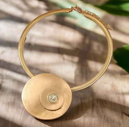Gold statement necklace with large 2.5-inch disc pendant and 14-inch collar chain with extender on satin background