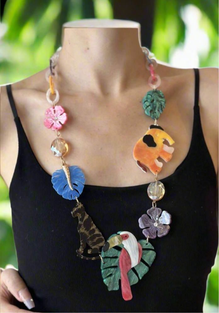 Colorful jungle-themed statement necklace with resin charms of a pink flamingo, orange elephant, leopard, tropical leaves, and flowers, connected by multicolored acrylic chain links.
