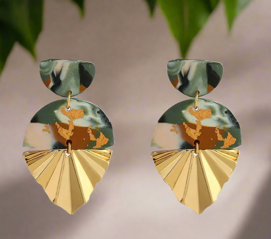 Pair of gold-tone Nala Half-Bottom Earrings with a sculpted half-fan leaf design, placed on a dark textured background.
