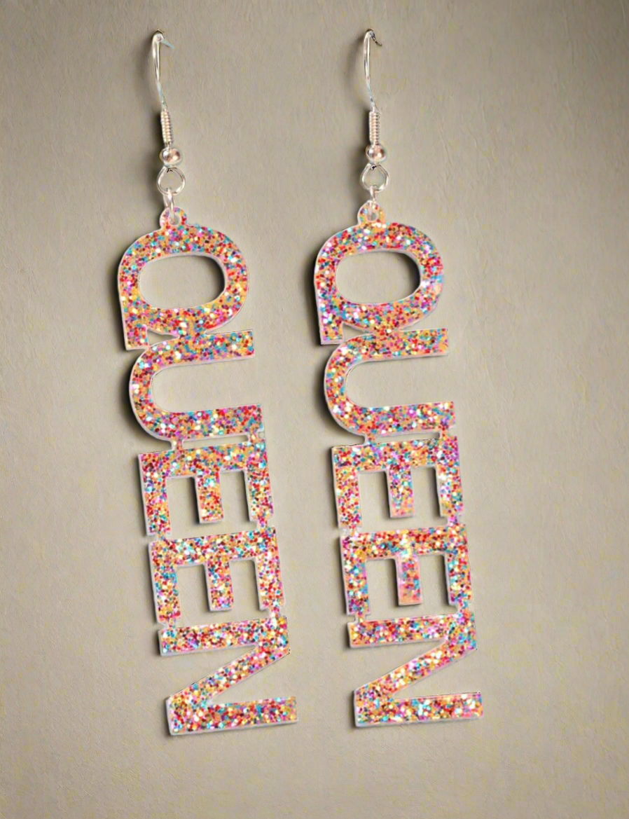 Sparkling glitter “QUEEN” dangle earrings on a light blue background, perfect for bold and stylish women.