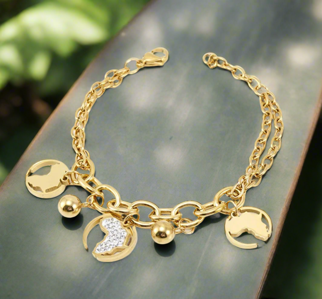 “Gold Africa charm bracelet with double link chain, gold map cutouts, rhinestone accents, and polished gold spheres, displayed on a white background.”
