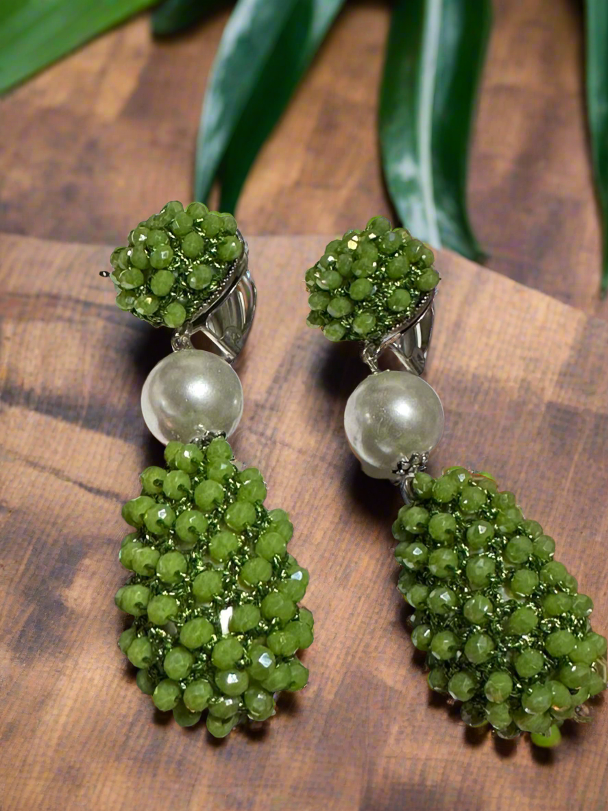 Elegant drop earring featuring clustered olive-green beads, a large faux pearl, and a teardrop bead cluster, shown on an earring stand.