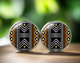 Round stud earrings featuring a bold black, white, and mustard yellow Bogolan-inspired tribal pattern with geometric and zigzag details on a glossy finish.
