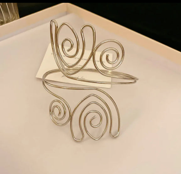 Silver-tone spiral swirl arm cuff for women, adjustable open bangle for upper arm, modern boho chic statement jewelry.

