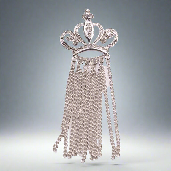 The Otre Rive Silver Tassel Brooch by Desiree W.A.R Store is a silver crown brooch featuring sparkling rhinestones and cascading chain tassels.